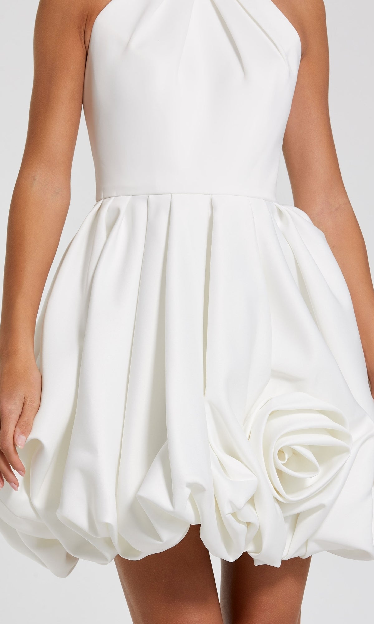A woman wears the Short Bubble-Hem Party Dress: Mac Duggal 20707, a sleeveless white satin dress featuring a bubble hem and a large rosette detail near the bottom.